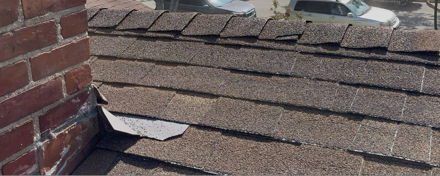 Aging asphalt shingles with surface cracking and granule loss on a San Gabriel home before restoration